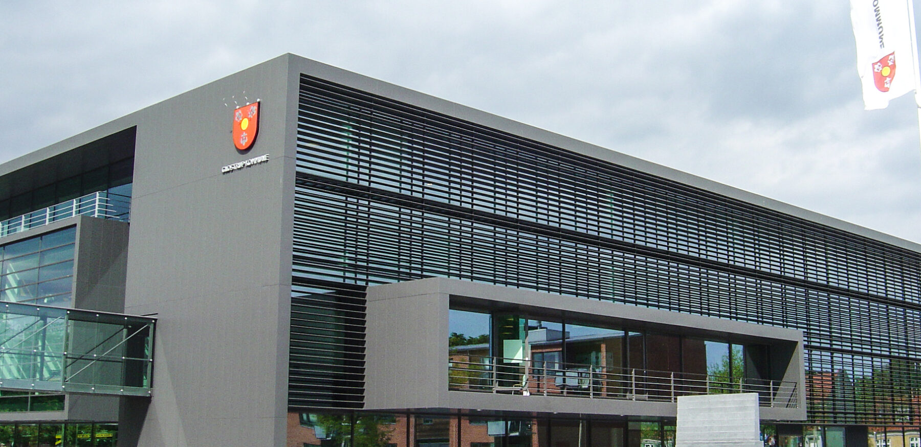 Modern facade of Glostrup Municipality’s town hall east wing with large horizontal louvres and glass bridge