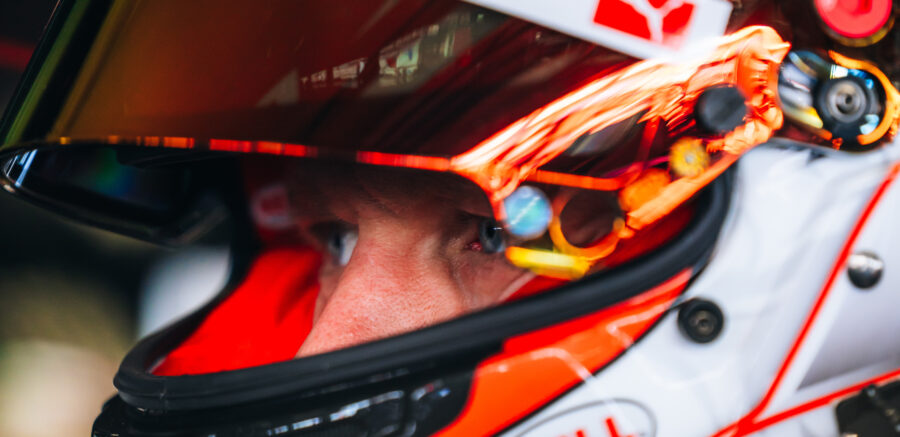 Close-up of Kevin Magnussen wearing a racing helmet with reflective visor, intensely focused before a race