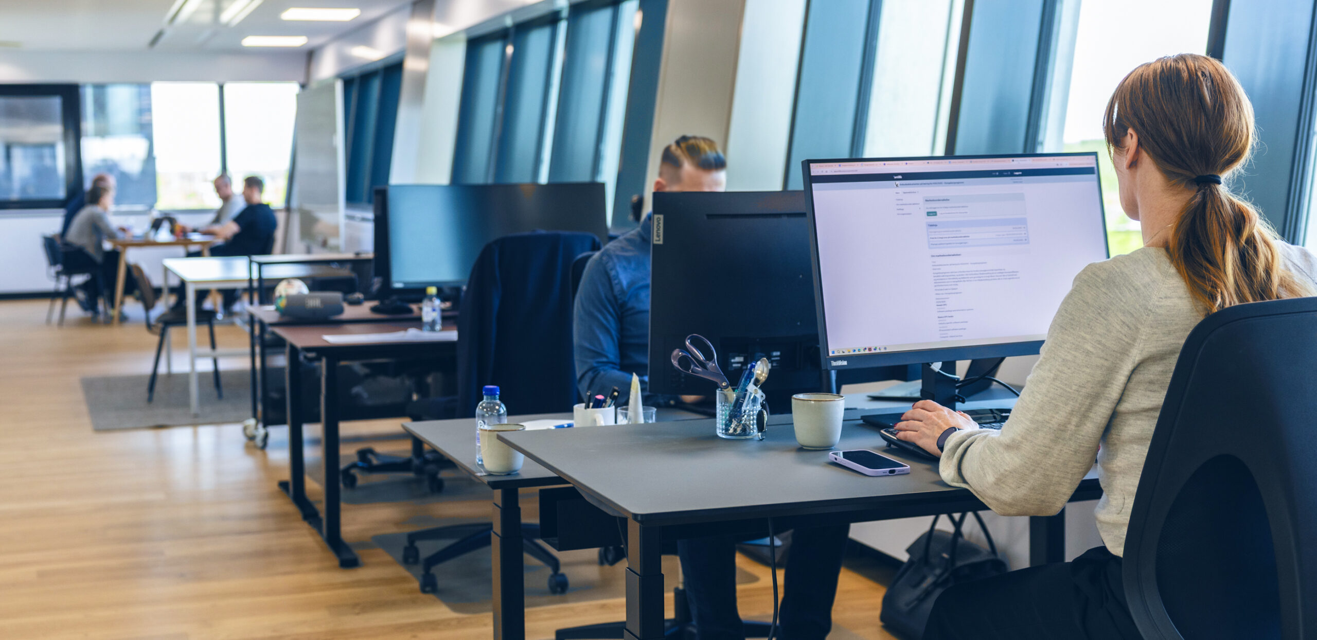 Modern open-plan office with employees working at desks and computers
