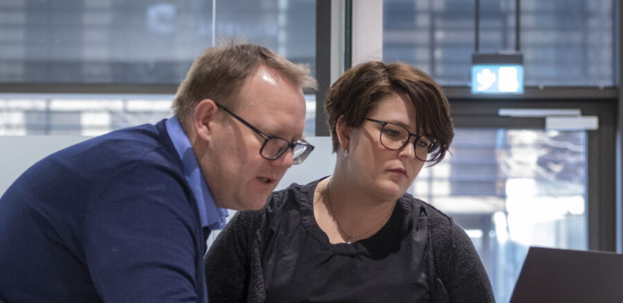 Two professionals collaborating over a laptop in a modern office setting