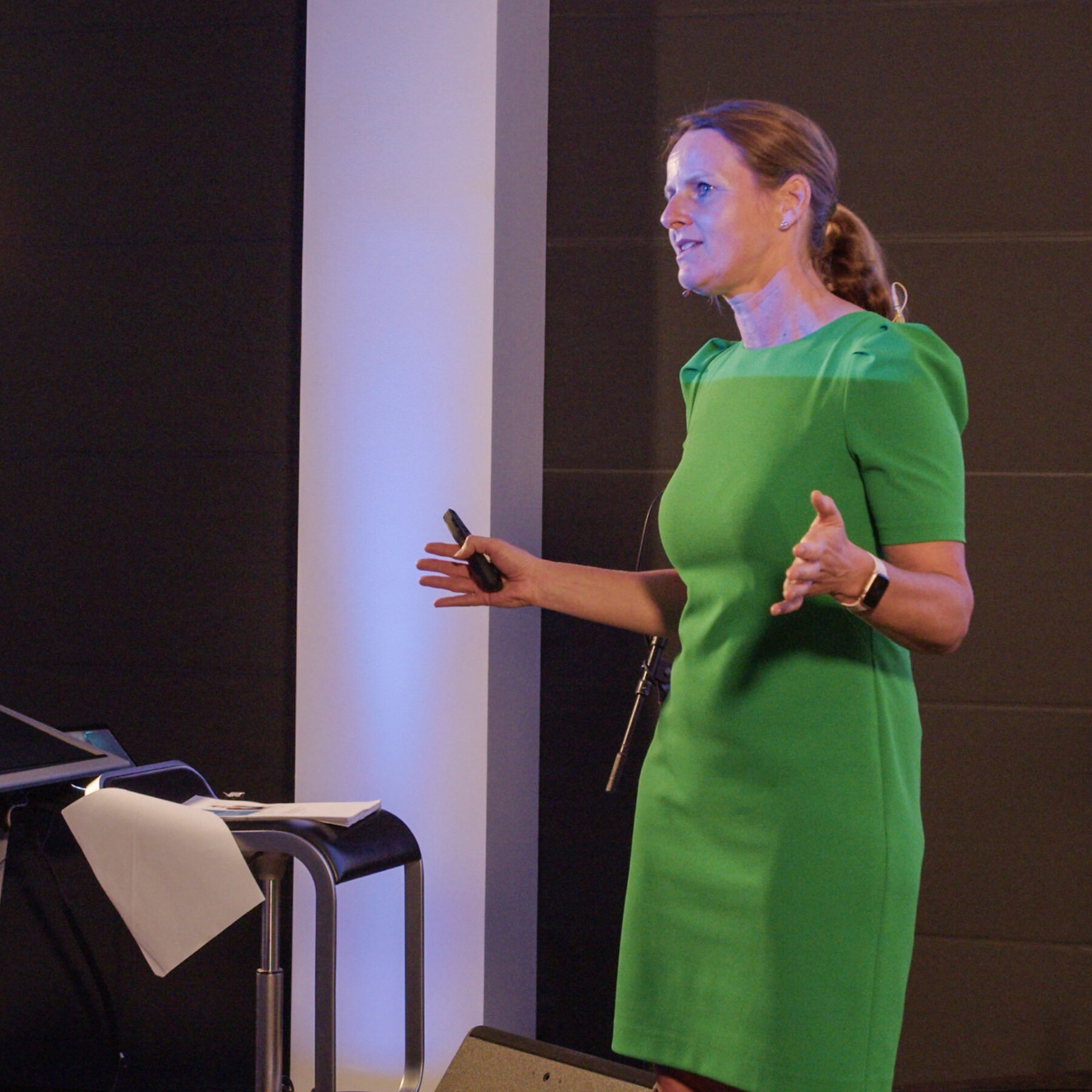 Female presenter in green dress delivering a talk with confidence at Intellis Brugerkonference 2023.