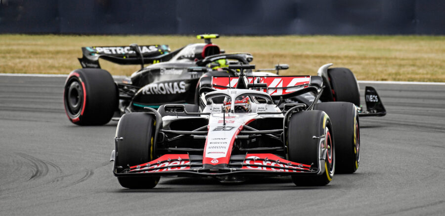 Haas F1 car driven by Kevin Magnussen ahead of Mercedes during a Formula 1 Grand Prix race.