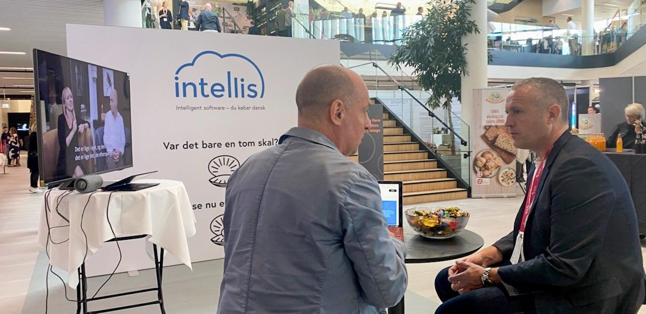 Two men in conversation at the Intellis exhibition booth during a business conference