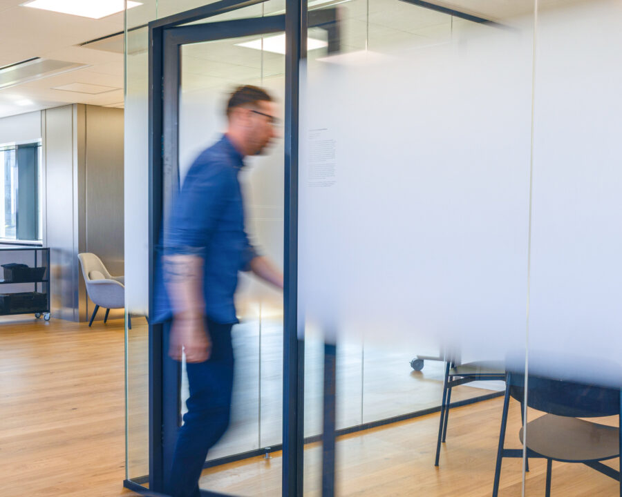Man walking into a glass meeting room at the Intellis office, with modern Scandinavian interior design and natural light.