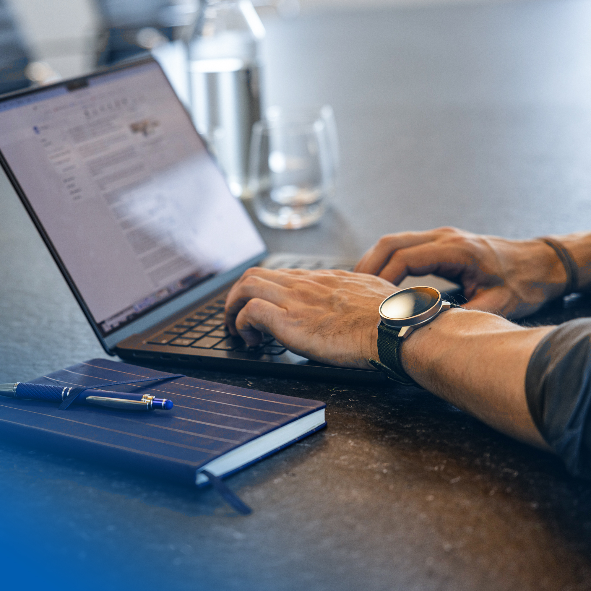 Person using a laptop next to a notebook and pen, illustrating streamlined digital procurement processes through technology.