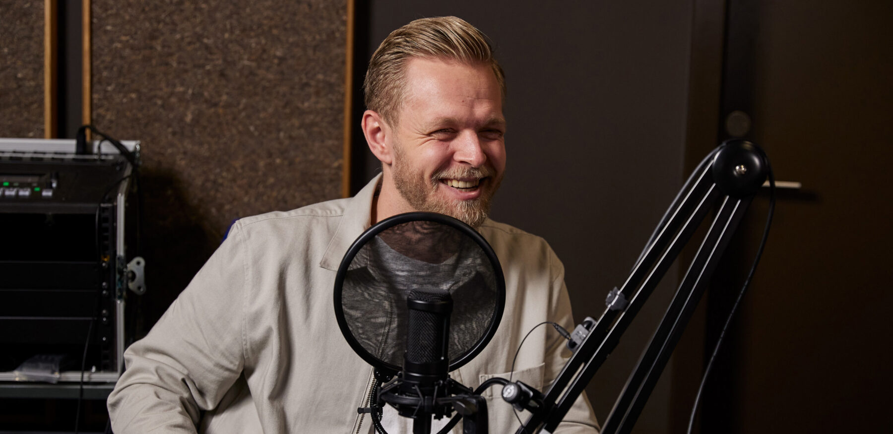 Man smiling during podcast recording at Intellis with a microphone in front of him
