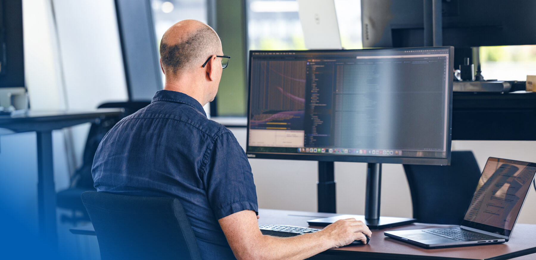 Software developer at Intellis working attentively on programming tasks at a dual-monitor workstation.