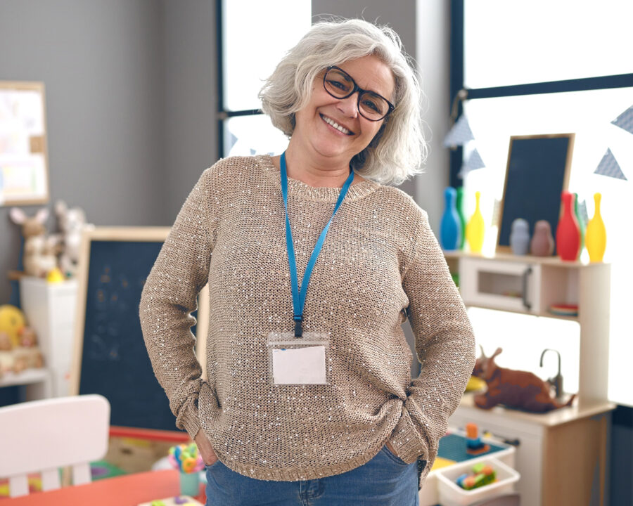 Smiling female public sector employee standing confidently in a brightly lit childcare or education setting