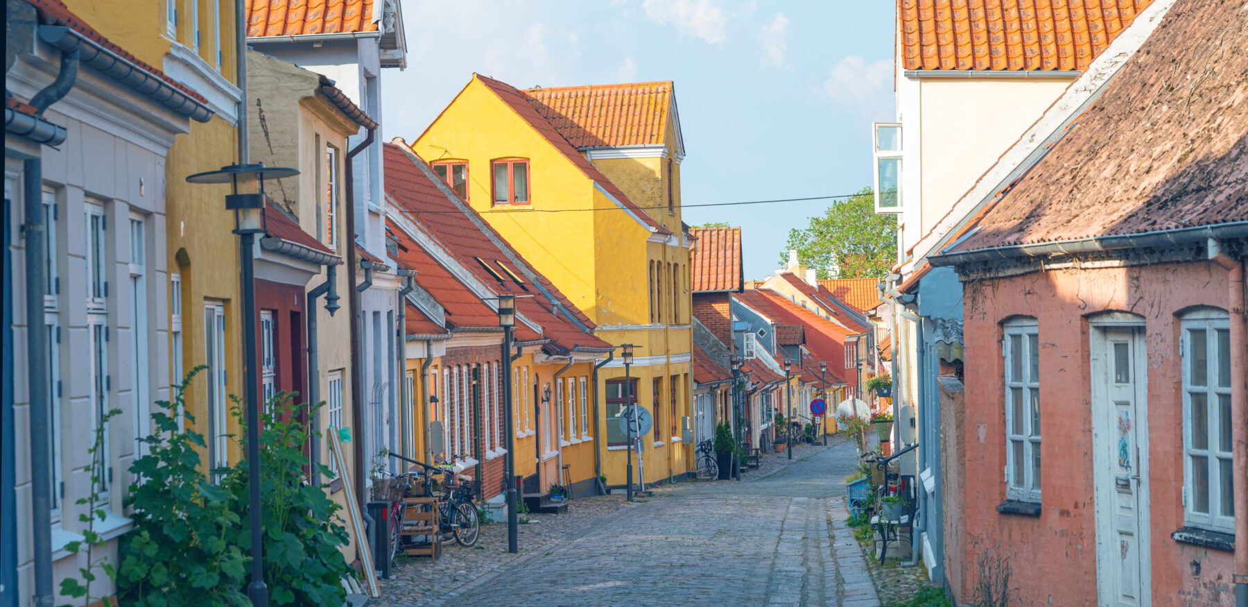 Charming cobblestone street in a Danish town with colourful traditional houses and bicycles outside.