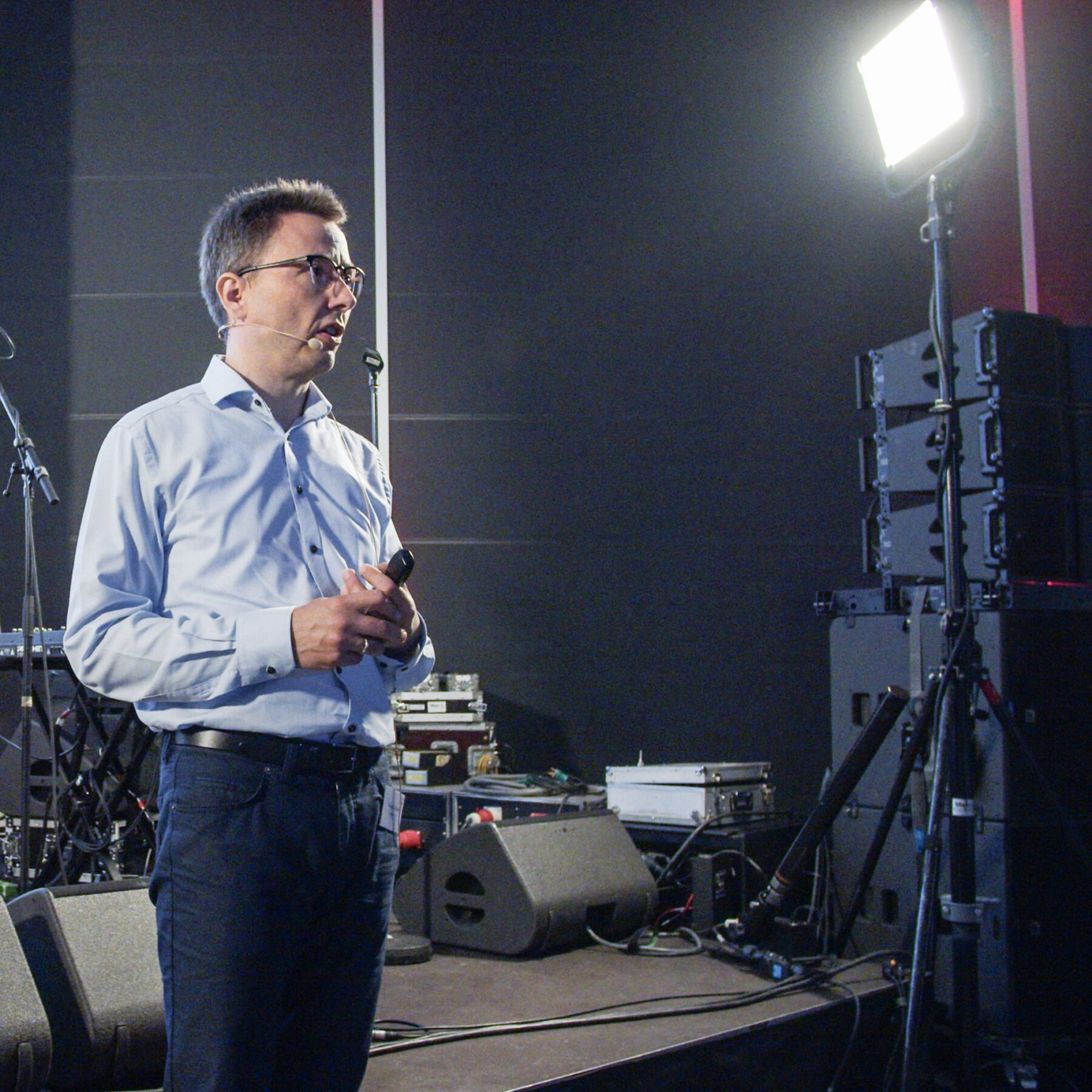 Male keynote speaker delivering a focused tech talk under studio lighting at Intellis Brugerkonference 2023.