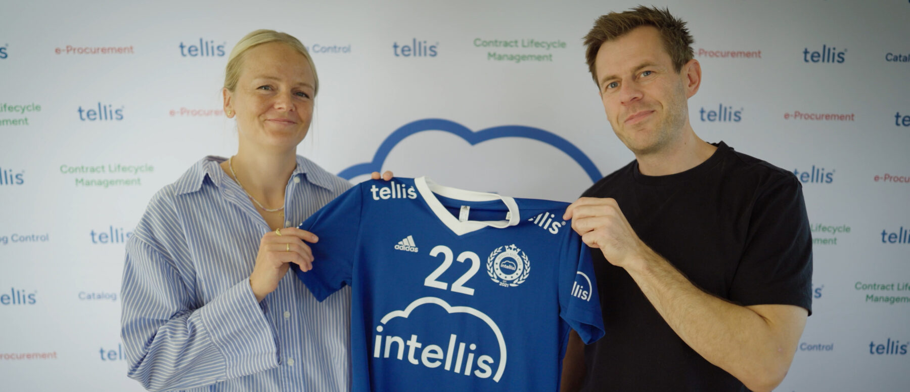 Two people holding up a blue handball jersey with the Intellis logo and number 22, representing a sponsorship partnership.