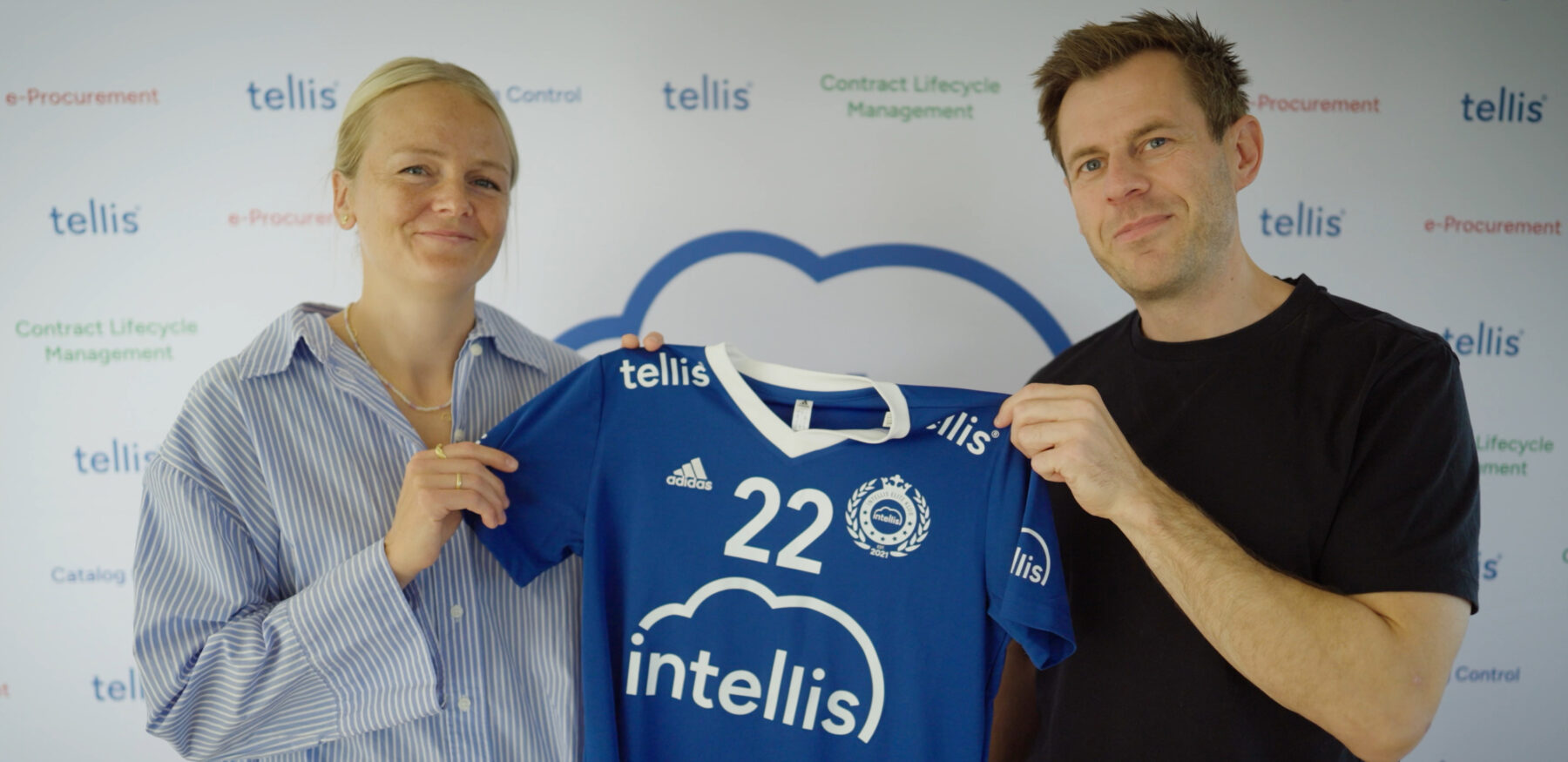 Two people holding up a blue handball jersey with the Intellis logo and number 22, representing a sponsorship partnership.
