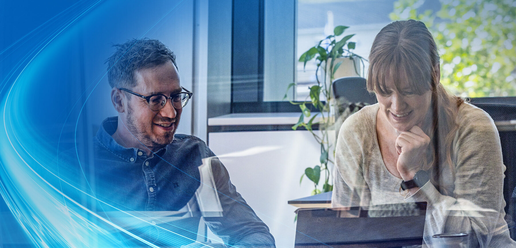Two colleagues collaborating in a modern office, smiling while discussing a project on a laptop, with a blue digital wave overlay.