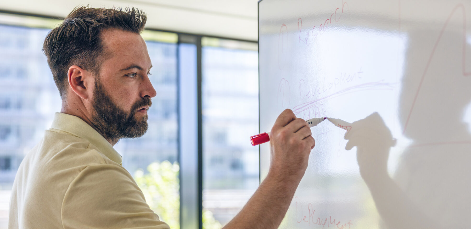 Man writing on a whiteboard during a strategy session at Intellis office