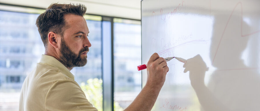 Man writing on a whiteboard during a strategy session at Intellis office