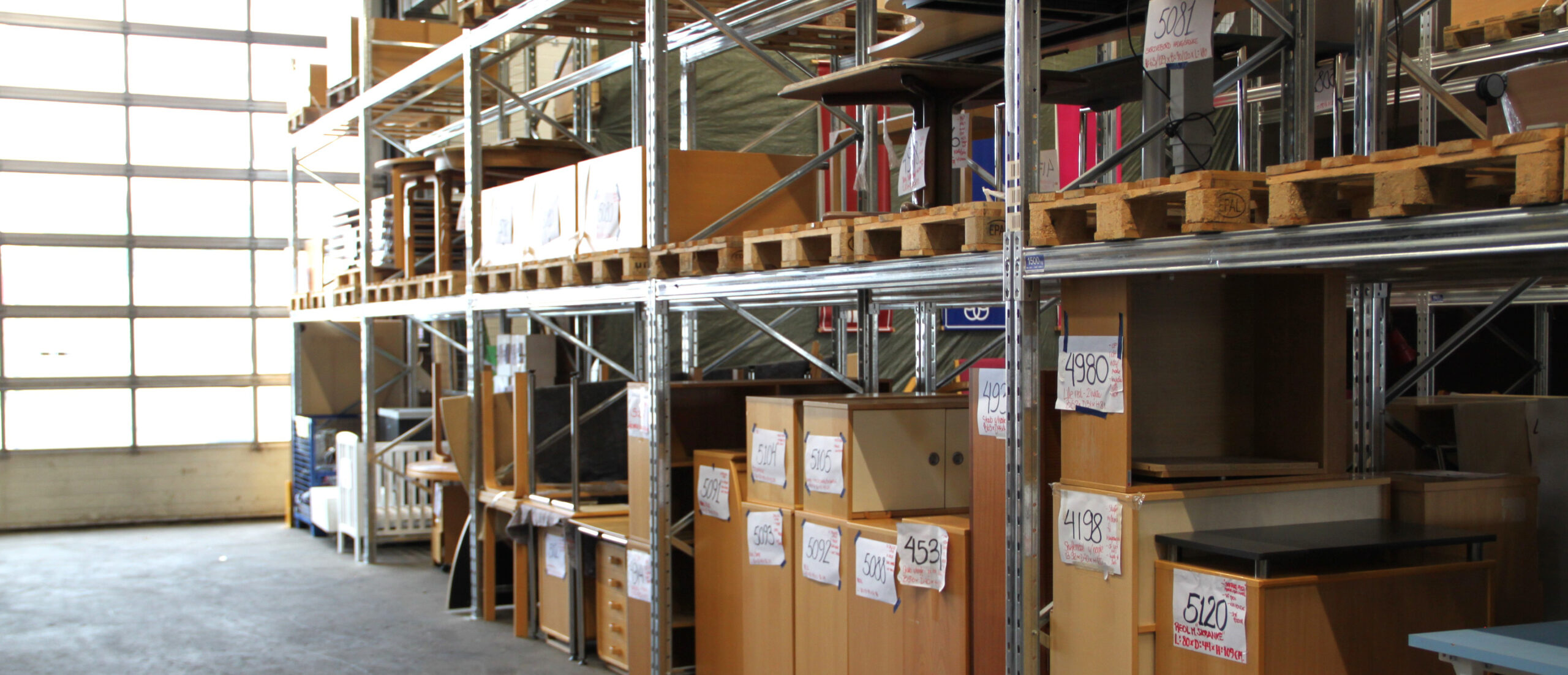 Interior of Kolding Municipality’s furniture warehouse with shelves of reused office furniture.
